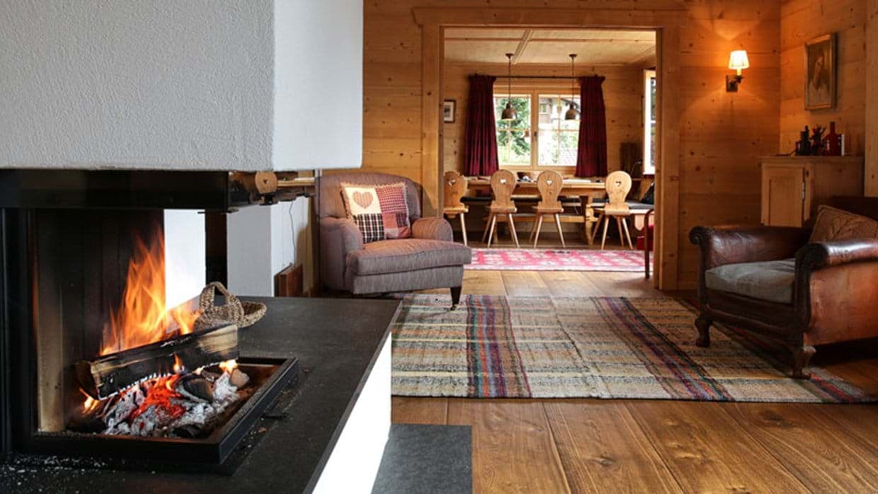 Wood-paneled living room with wood-burning fireplace and dining area beyond