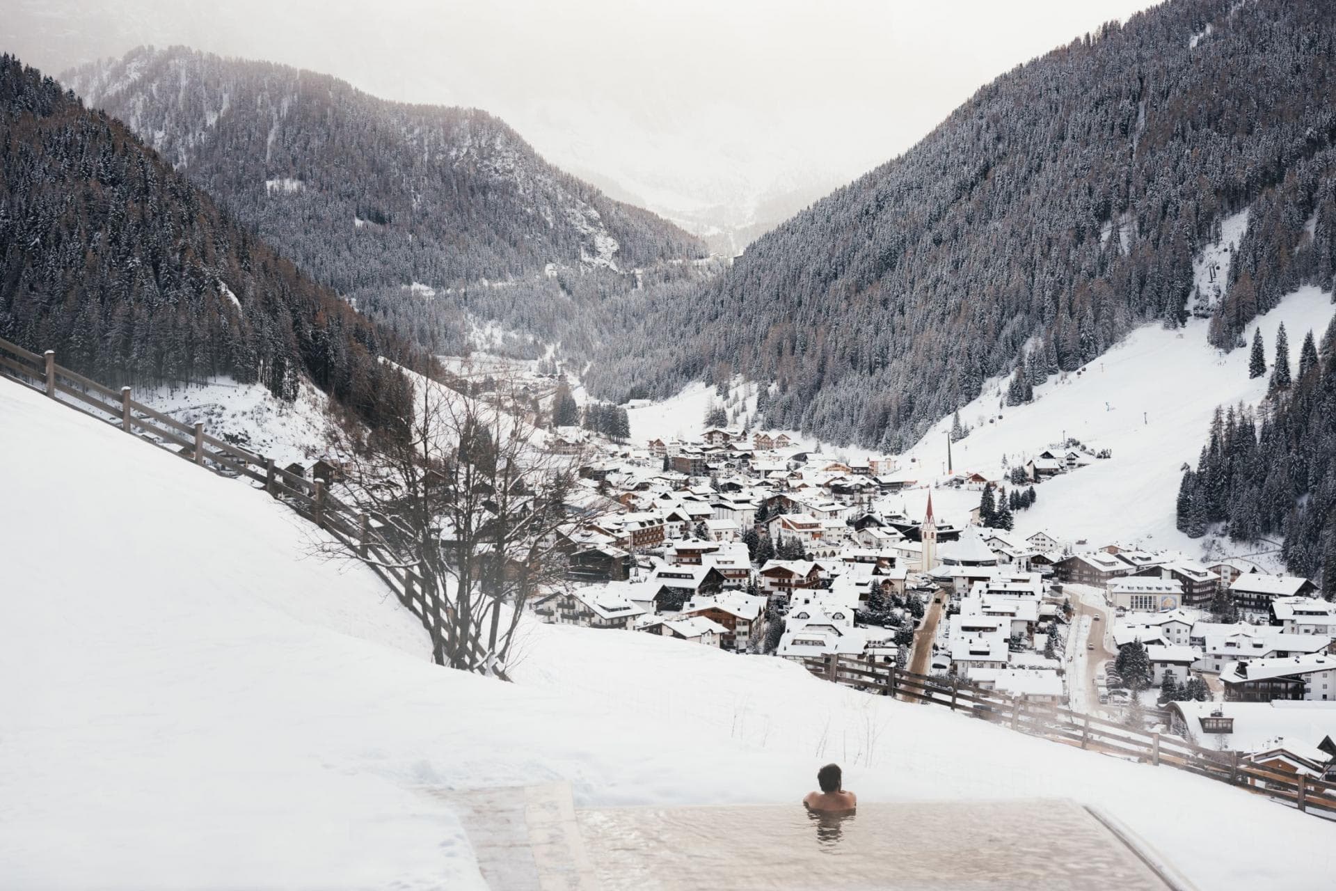 Heated infinity pool with panoramic views of snow-covered alpine village