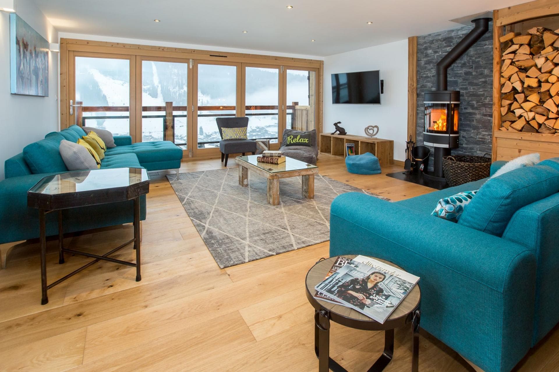 Living room with wood-burning stove and mountain views through bifold doors
