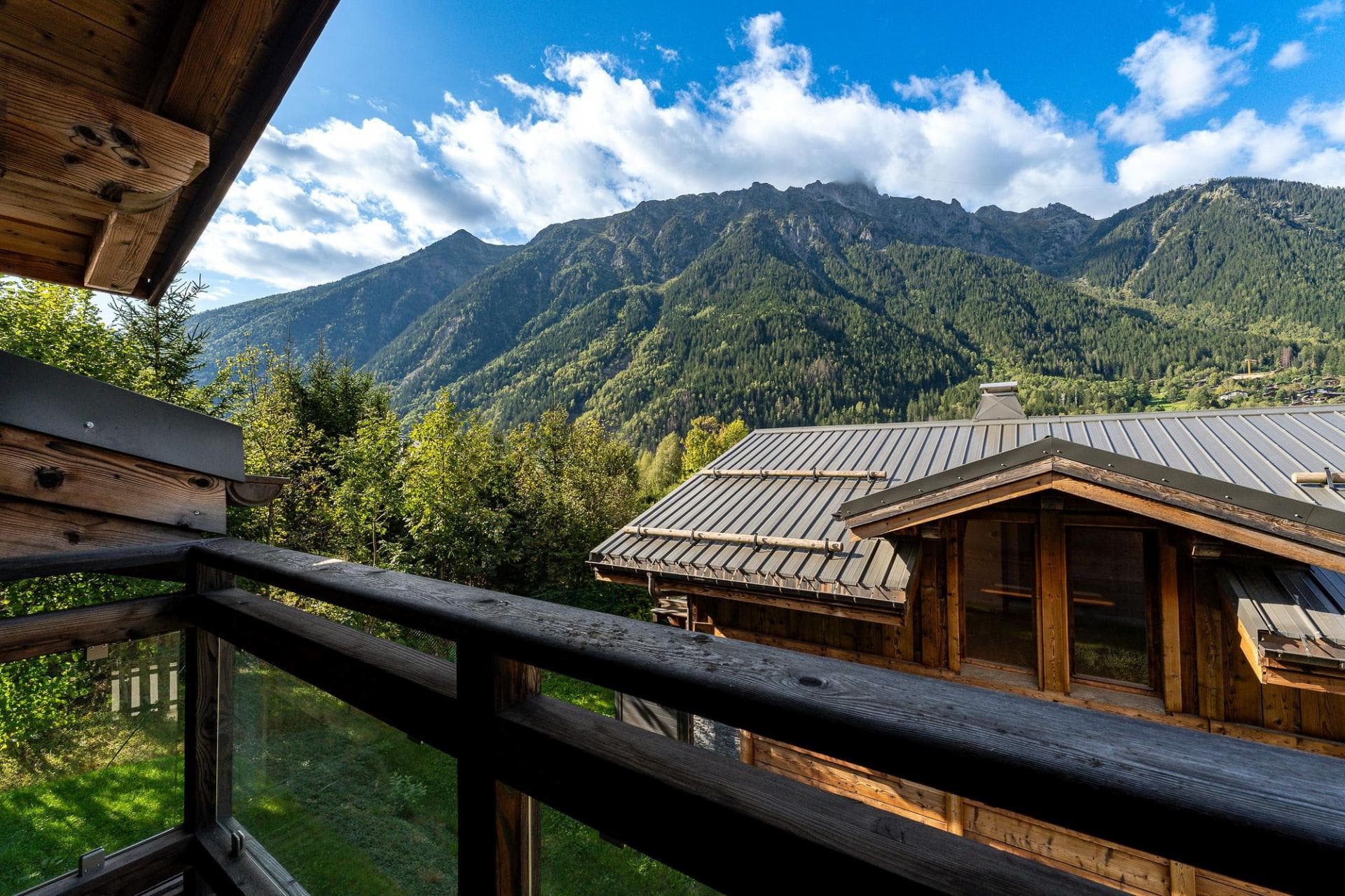 Private wooden balcony with mountain views and glass safety railings