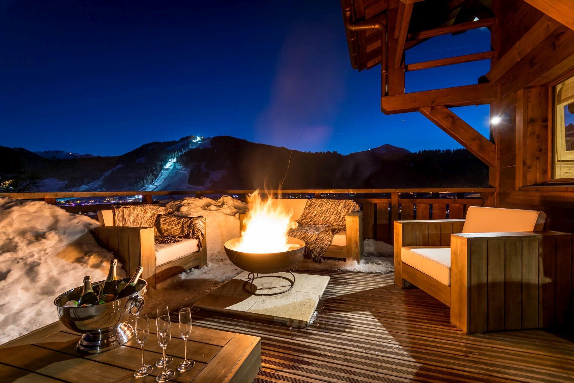 Deck with wood-burning fire pit and views of lit ski runs