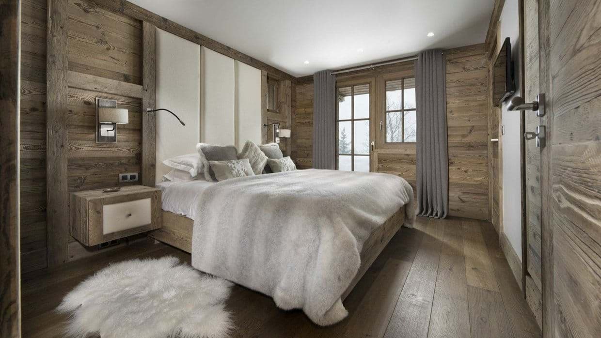 Wood-paneled bedroom with king bed and snowy balcony view