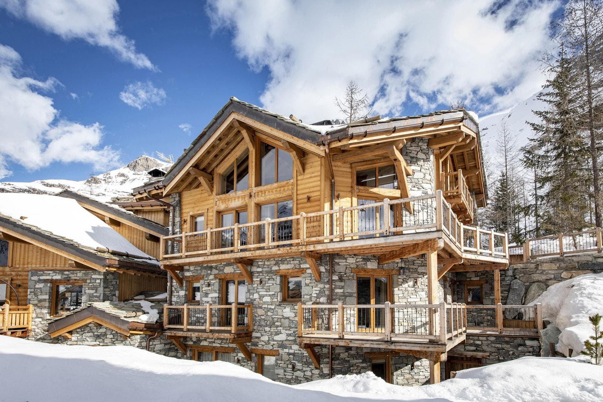 Ski-in chalet exterior with multi-level timber balconies and stone masonry