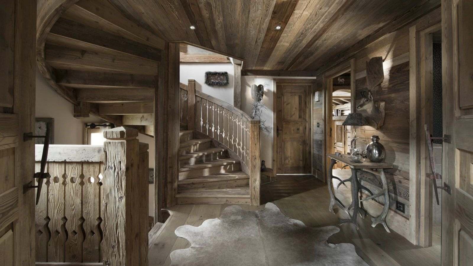 Entryway with curved wooden staircase and timber-paneled walls