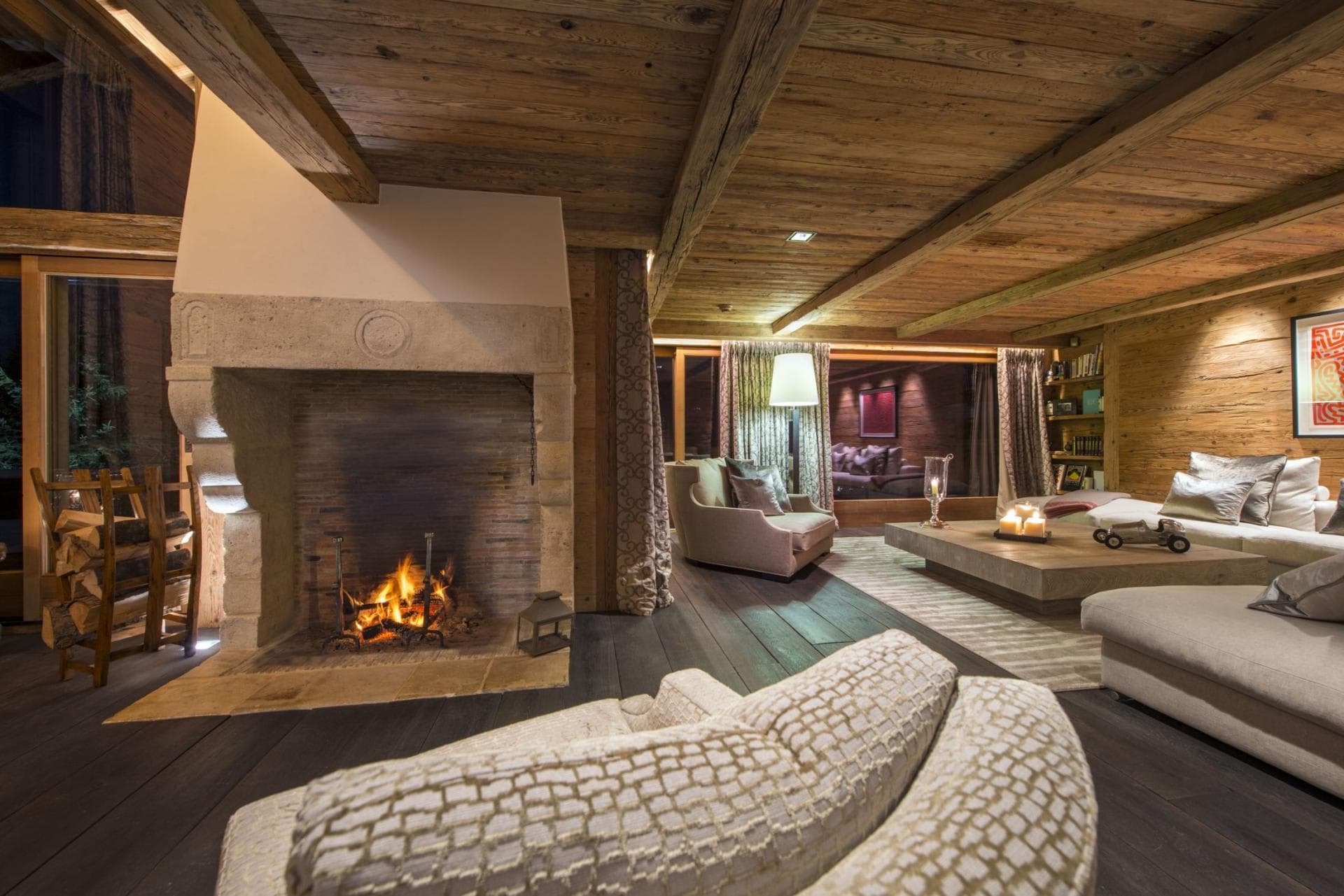 Living area with wood-burning stone fireplace and reclaimed timber ceilings
