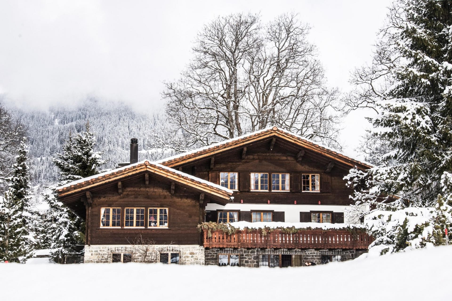 Chalet exterior with large balcony and snowy mountain backdrop