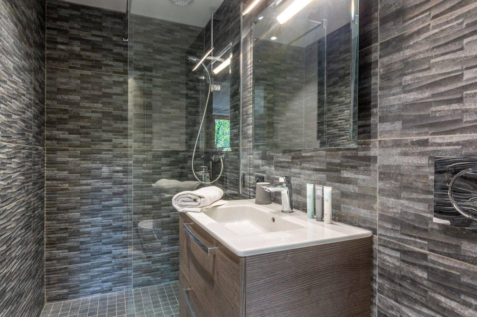 Bathroom with walk-in glass shower and textured wall tile