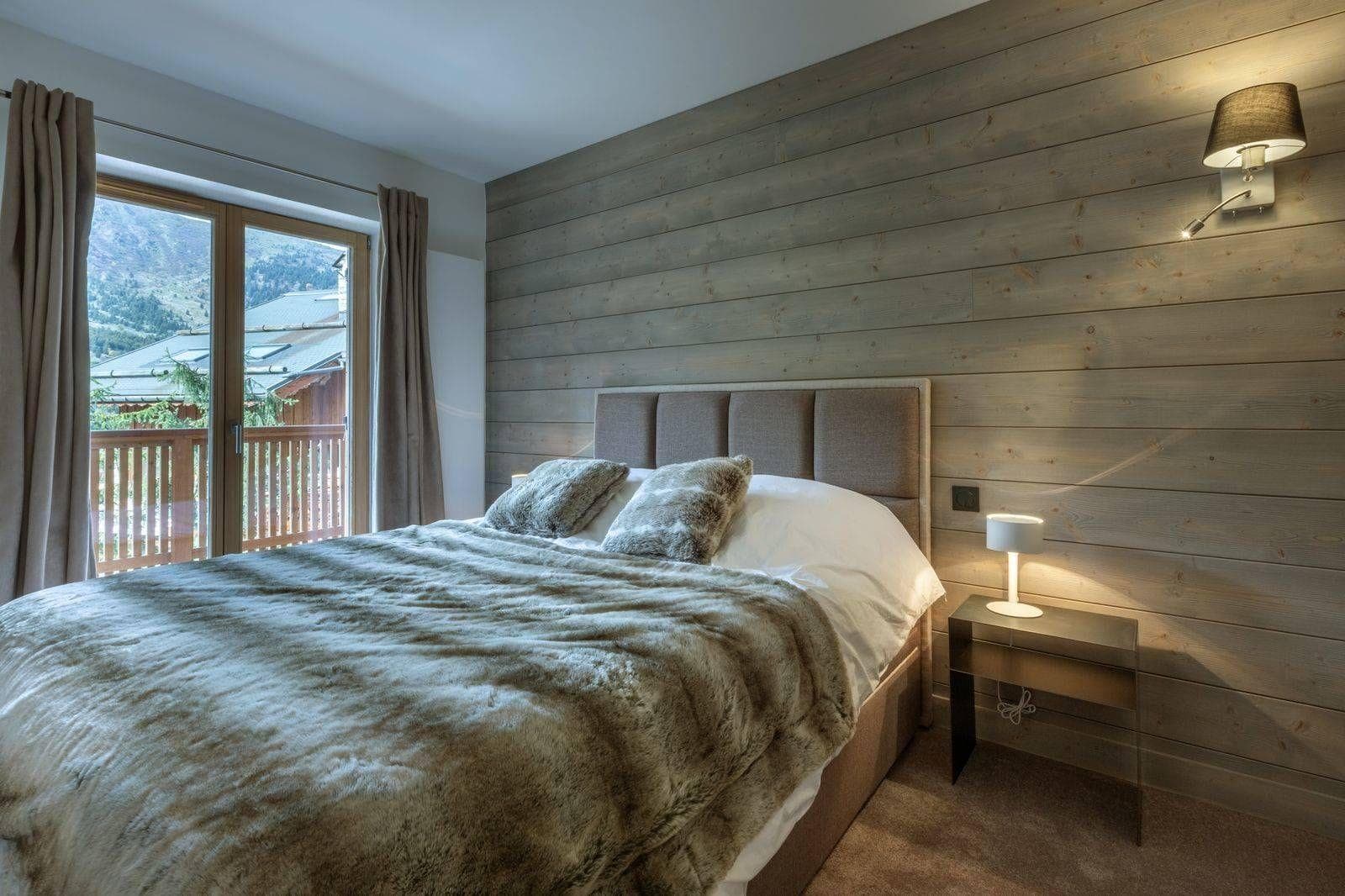 Bedroom with double bed, wood-paneled accent wall, and private balcony access