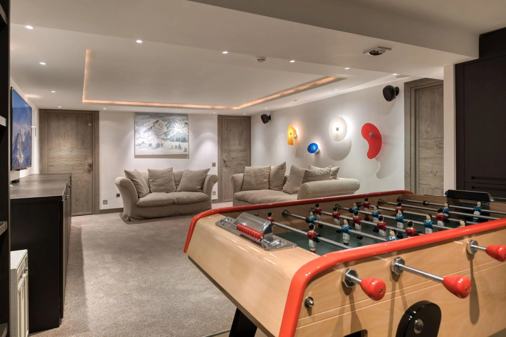 Media room with foosball table, wall-mounted speakers, and theater lighting