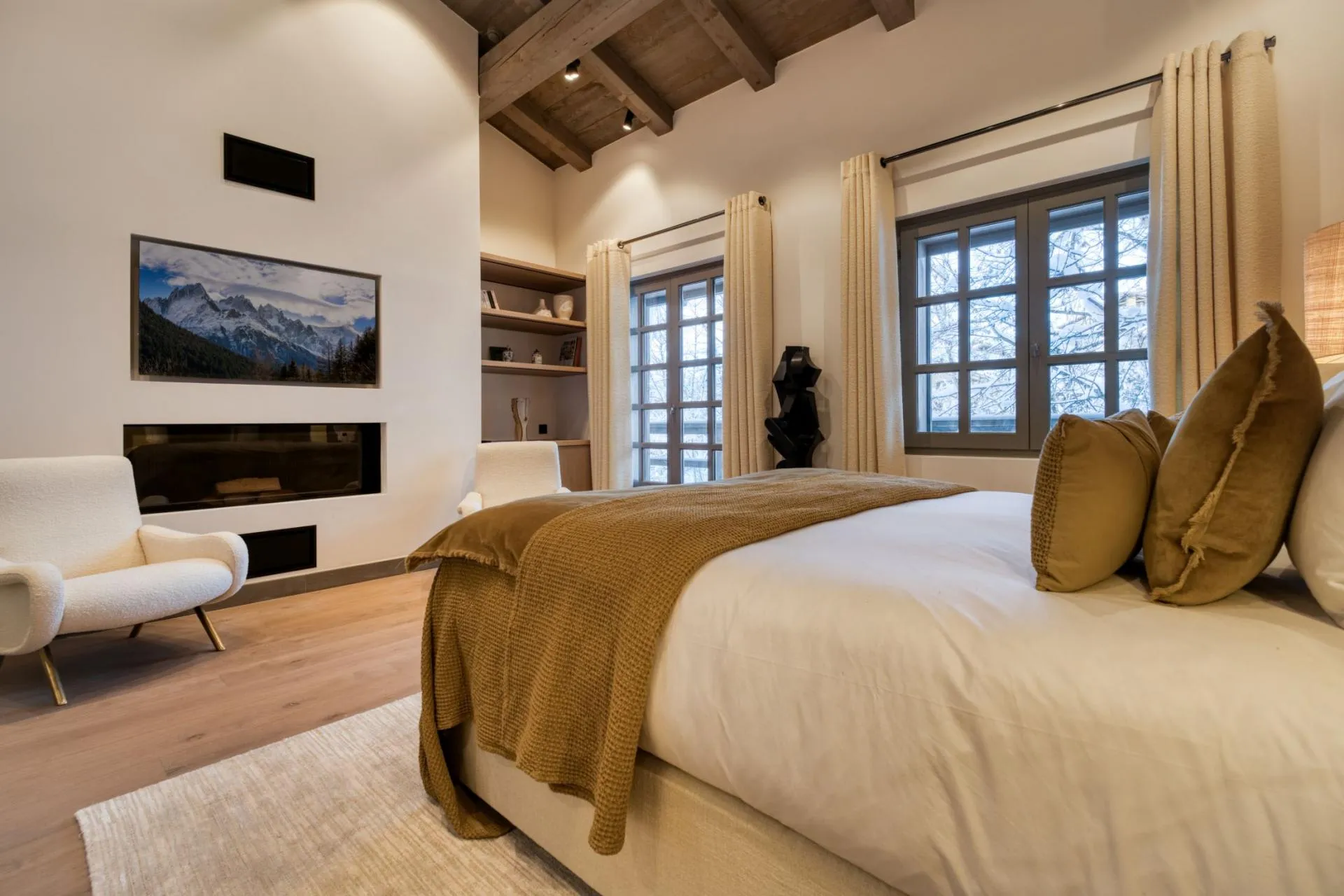 Primary bedroom with gas fireplace, Frame TV, and vaulted timber ceilings