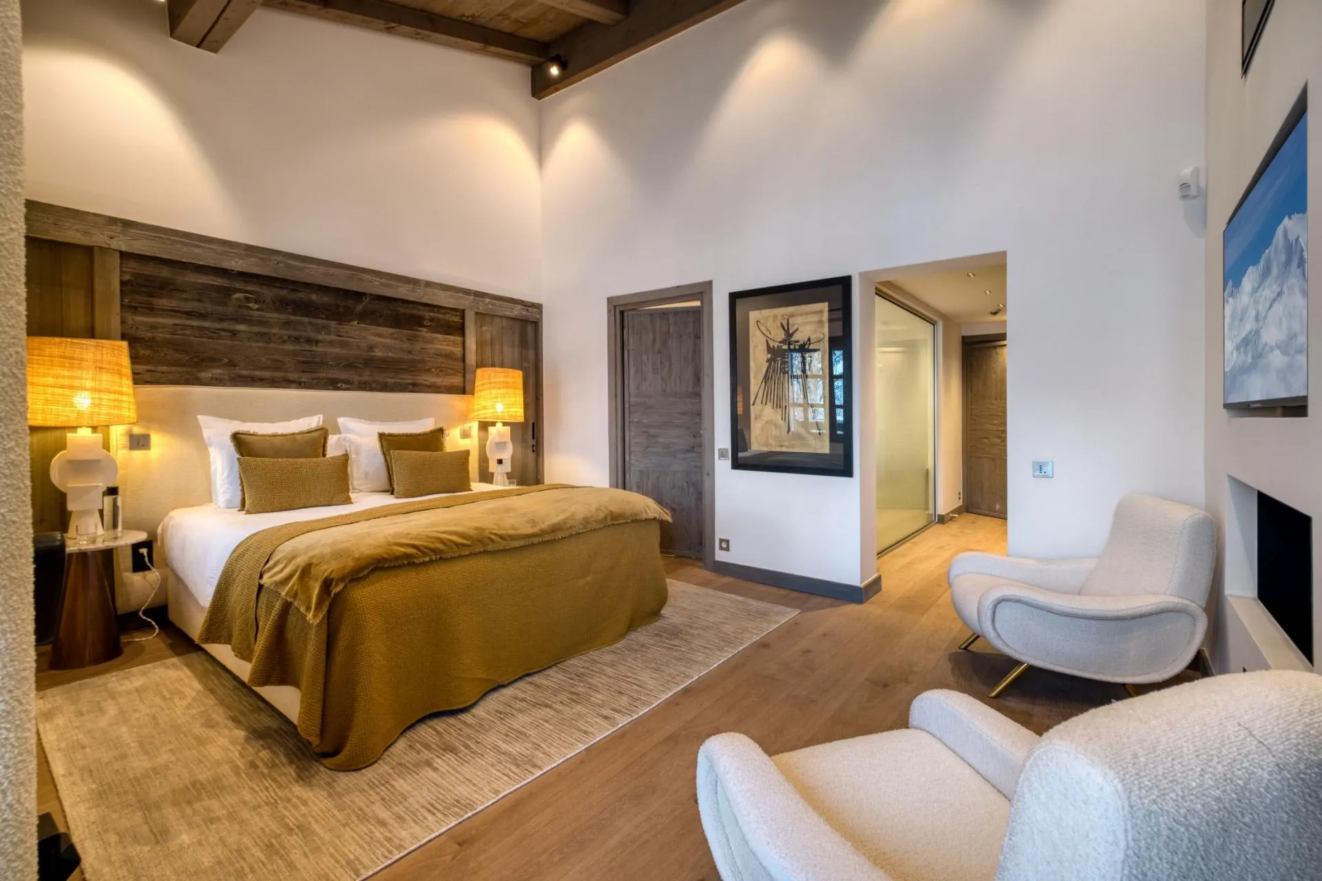 Primary bedroom with king bed, armchair seating, and en-suite access