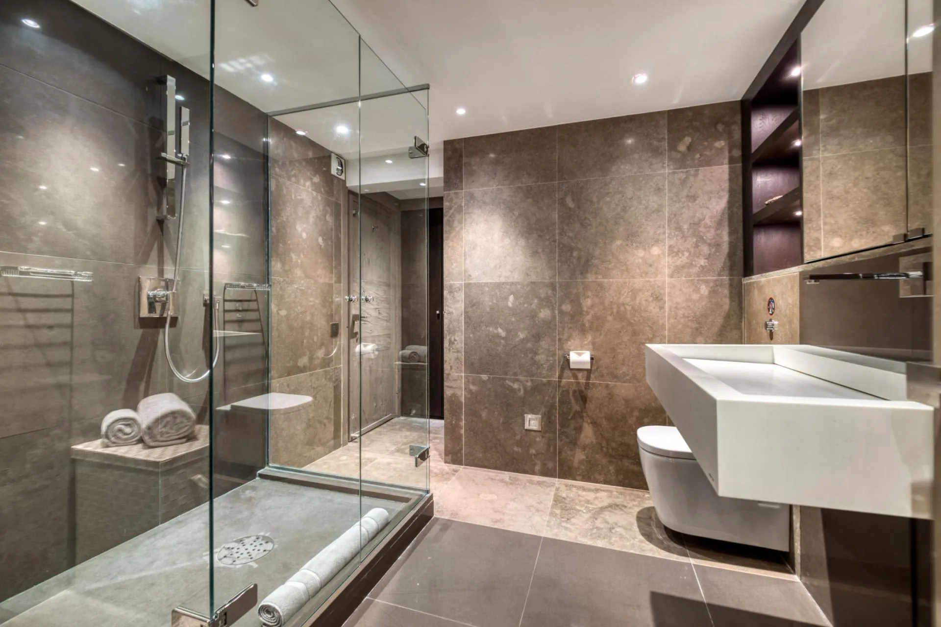Bathroom featuring glass-enclosed walk-in shower with rainfall head and stone tiling