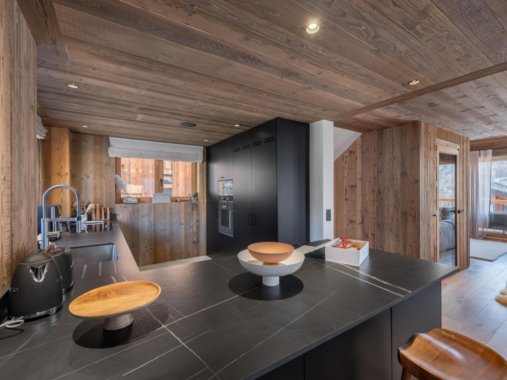 Kitchen with stone waterfall island, integrated Smeg appliances, and reclaimed wood paneling