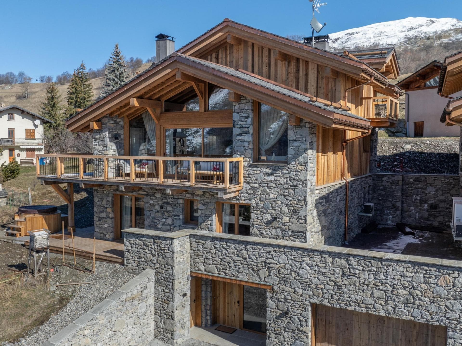 Stone and timber chalet exterior with cedar hot tub and mountain views