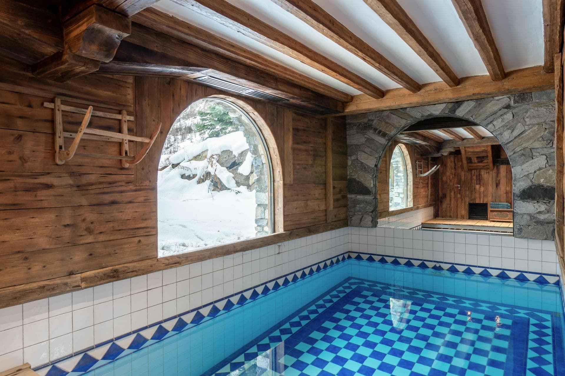 Indoor pool with mosaic tiling and snowy mountain views
