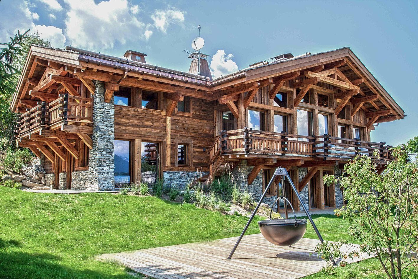 Timber-framed chalet exterior with wrap-around balcony and tripod fire pit