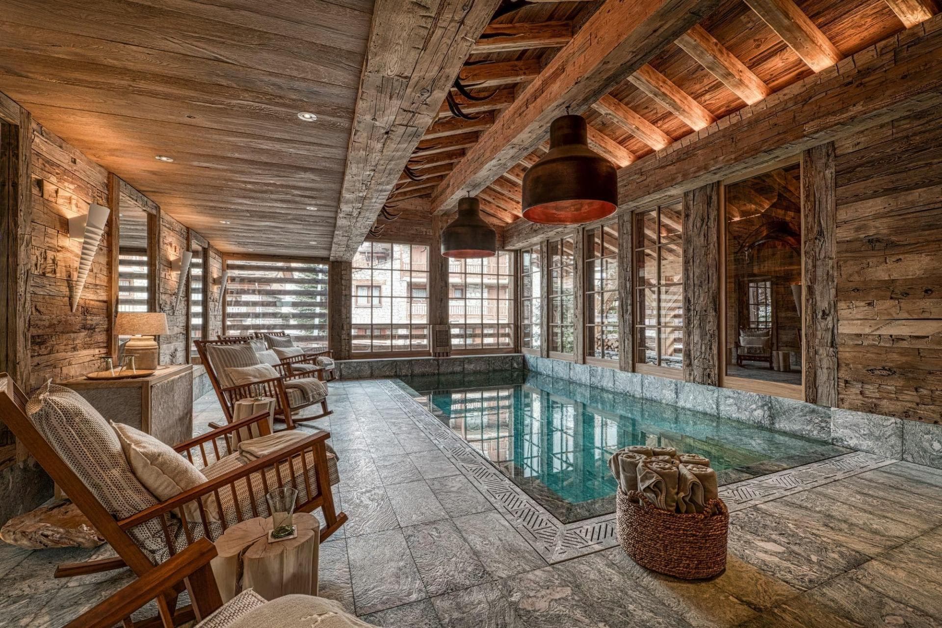 Indoor pool area with reclaimed wood beams and stone tile flooring