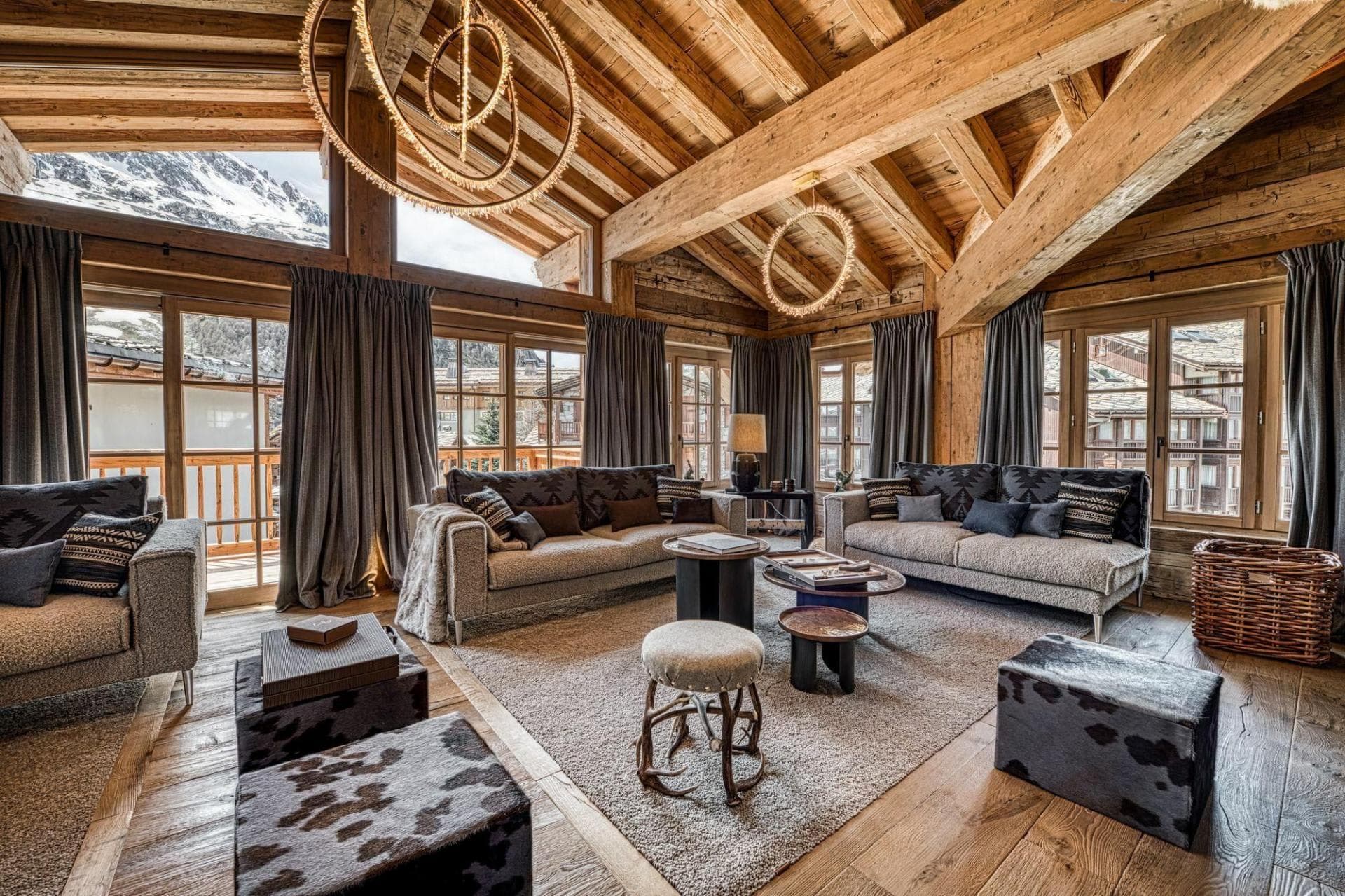 Living area with mountain views, vaulted timber ceilings, and balcony access