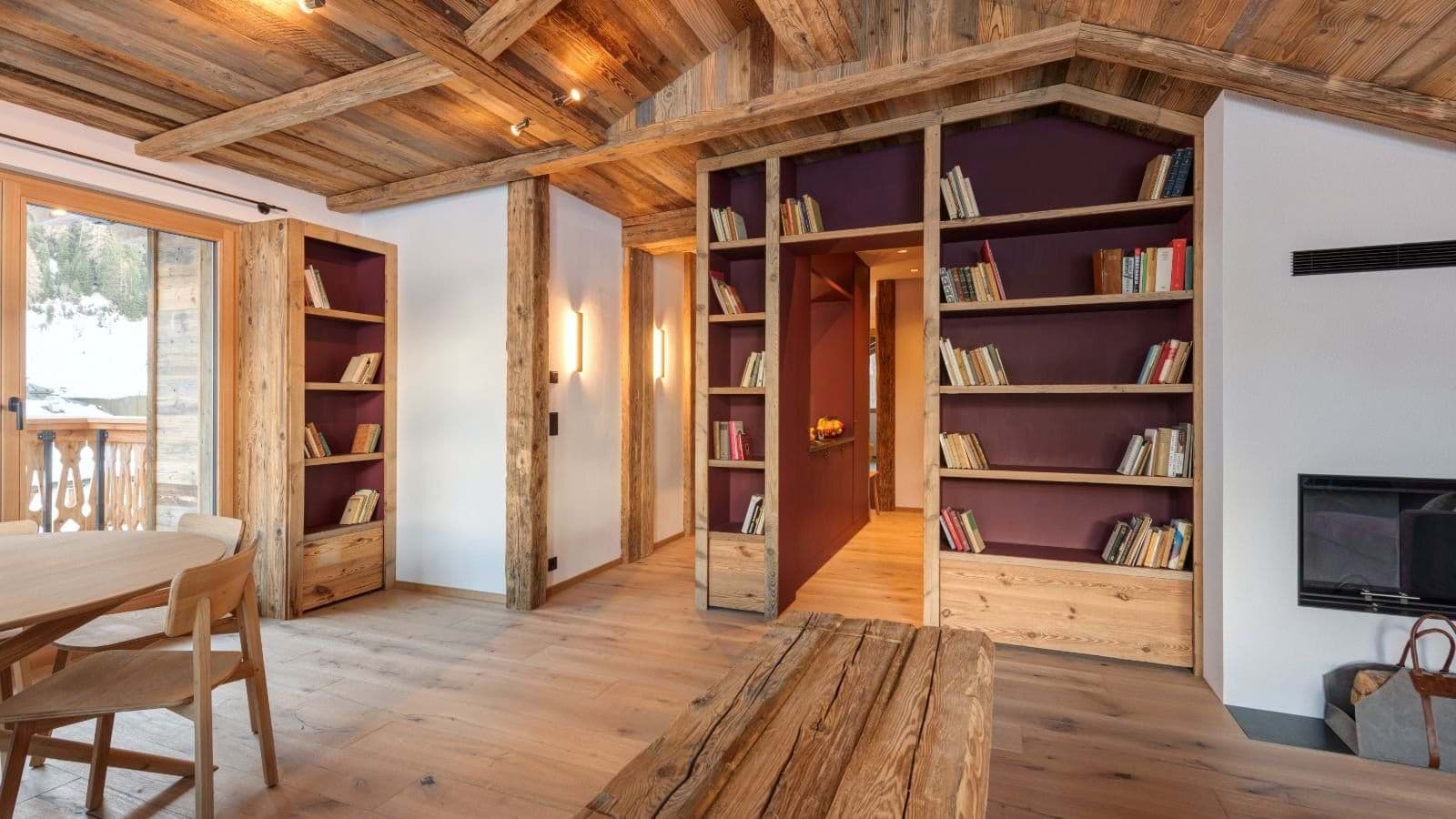 Living area featuring built-in library wall and wood-burning fireplace