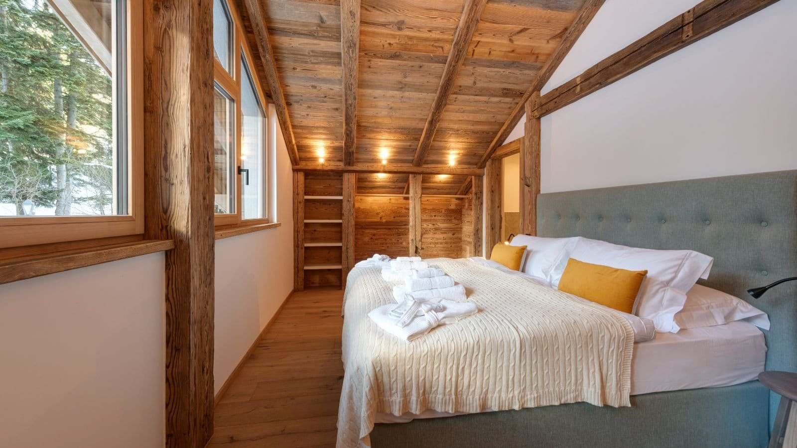 Bedroom with king bed, vaulted timber ceiling, and forest view
