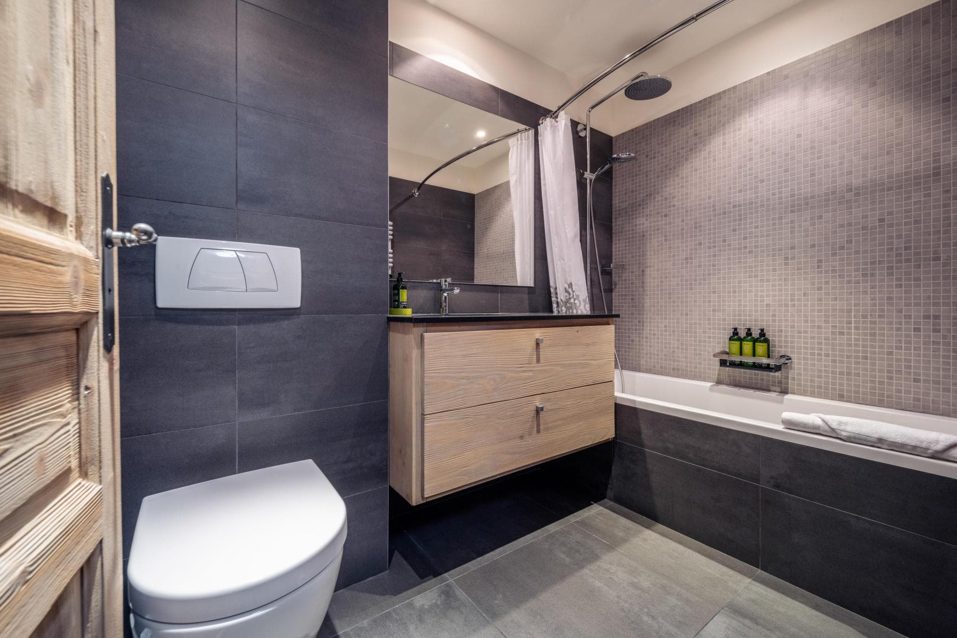 Bathroom featuring soaking tub with rainfall showerhead and floating wood vanity