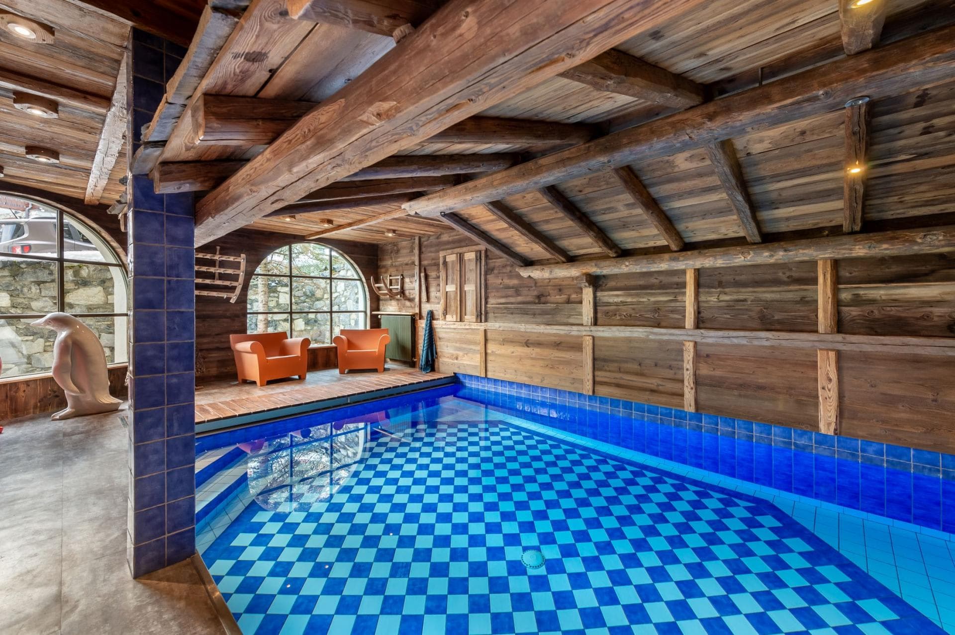 Indoor pool with checkered tile floor and timber beam ceiling