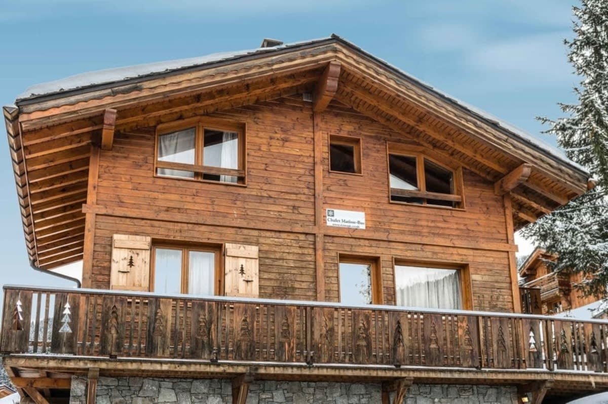 Timber chalet exterior with stone base and wrap-around balcony