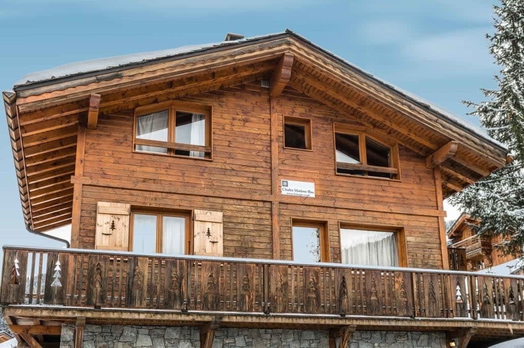Timber chalet exterior with stone base and wrap-around balcony