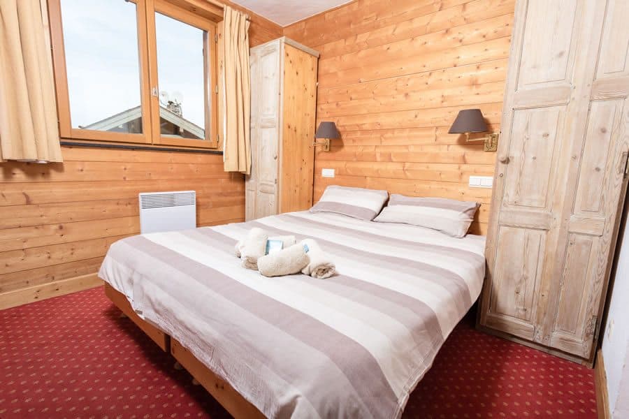 Wood-paneled bedroom with queen bed and dual built-in wardrobes