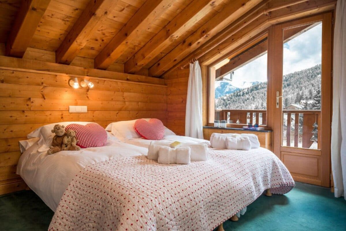 Guest bedroom with twin beds and mountain-view balcony access