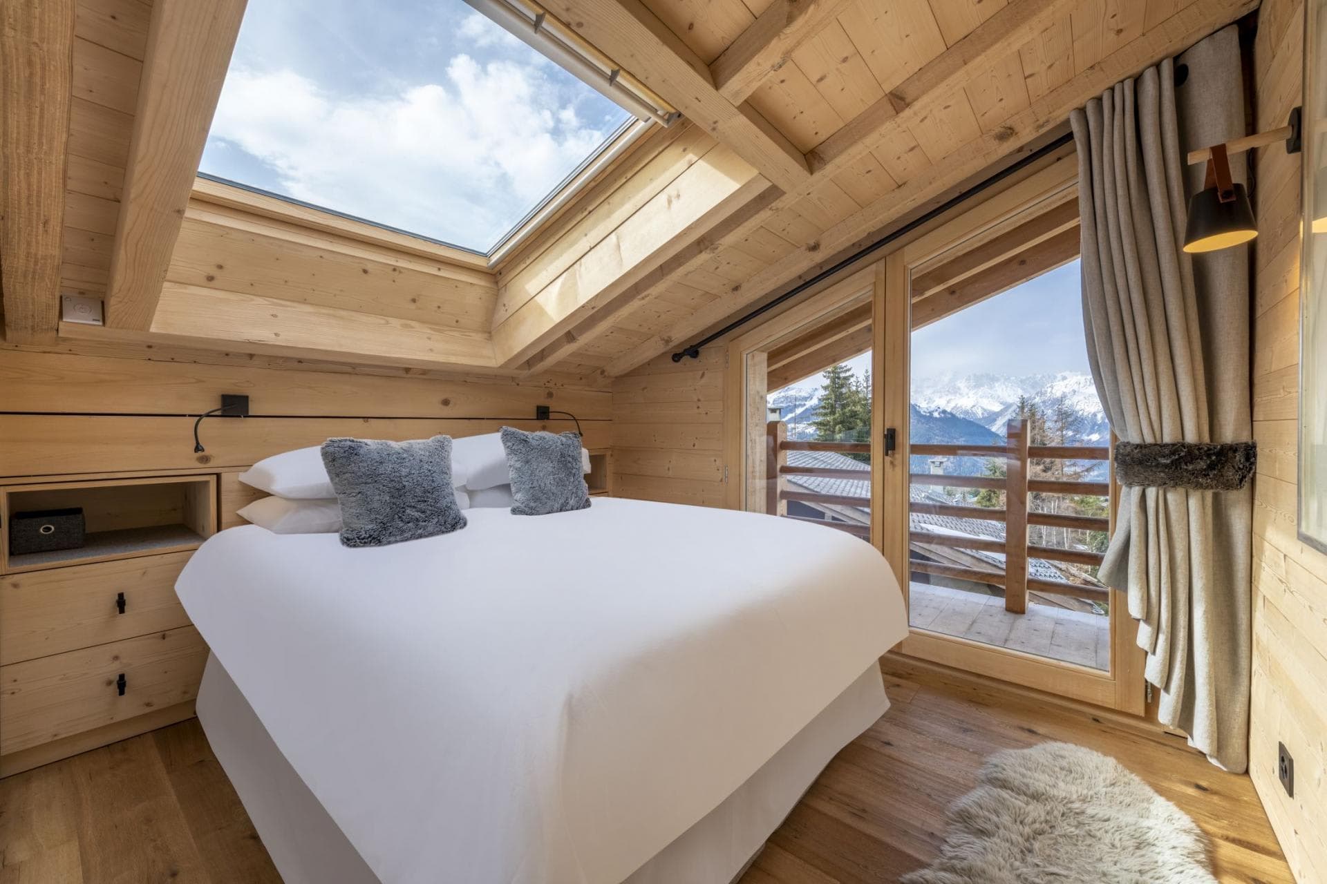 Bedroom with skylight above bed and balcony with mountain views