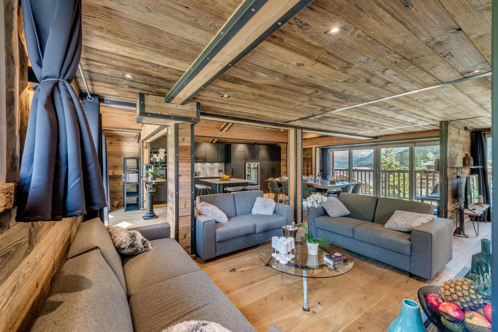 Open-plan living area with three sofas and mountain-view balcony