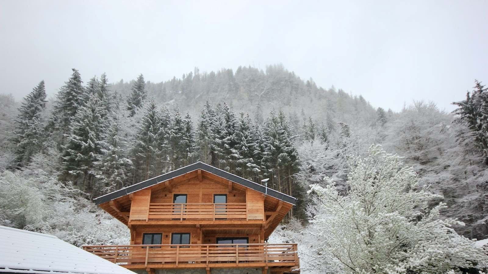Timber chalet exterior with private balconies and snow-covered forest backdrop