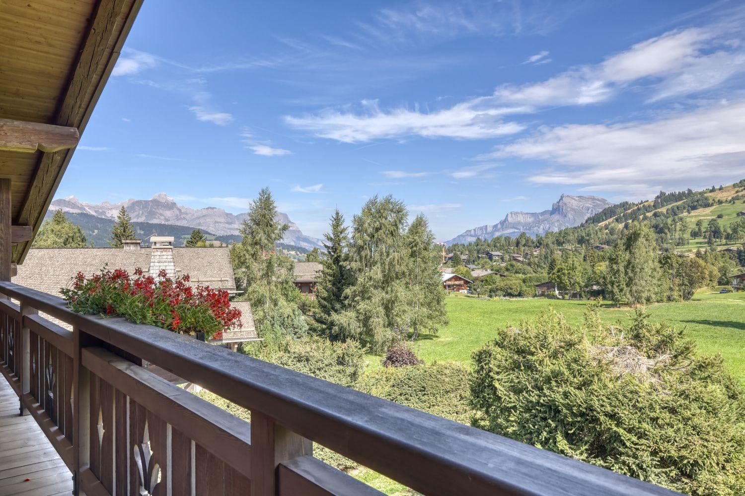 Private balcony with wooden railings and panoramic Alpine valley views