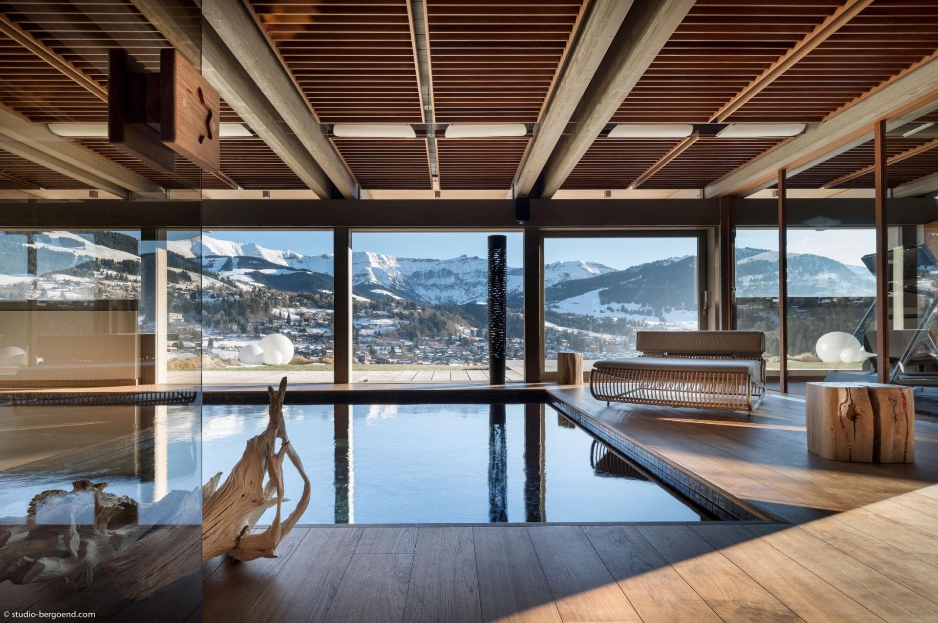 Indoor heated pool with mountain views and adjacent wood deck lounge