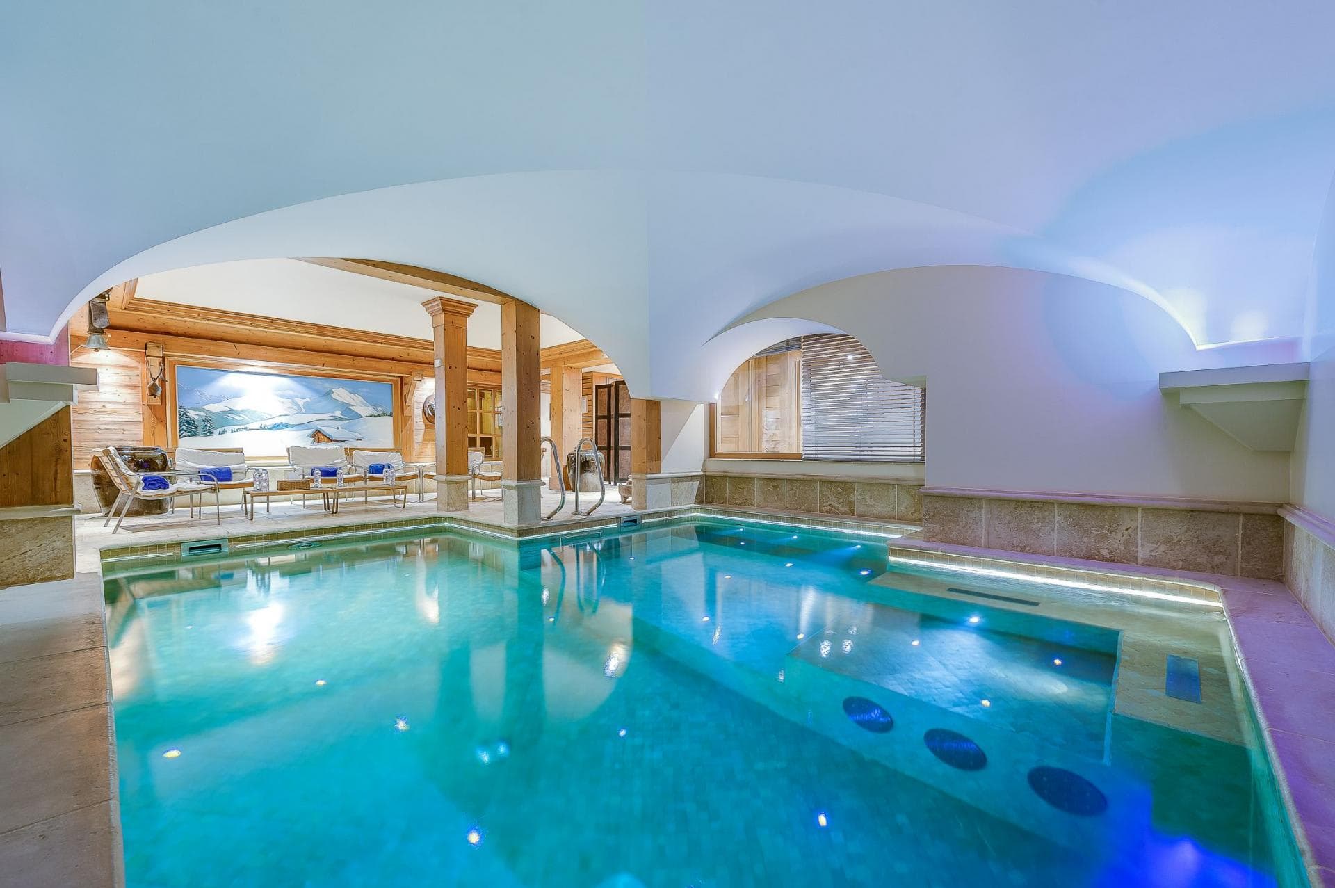 Indoor pool and integrated hot tub with vaulted ceilings and lounge seating