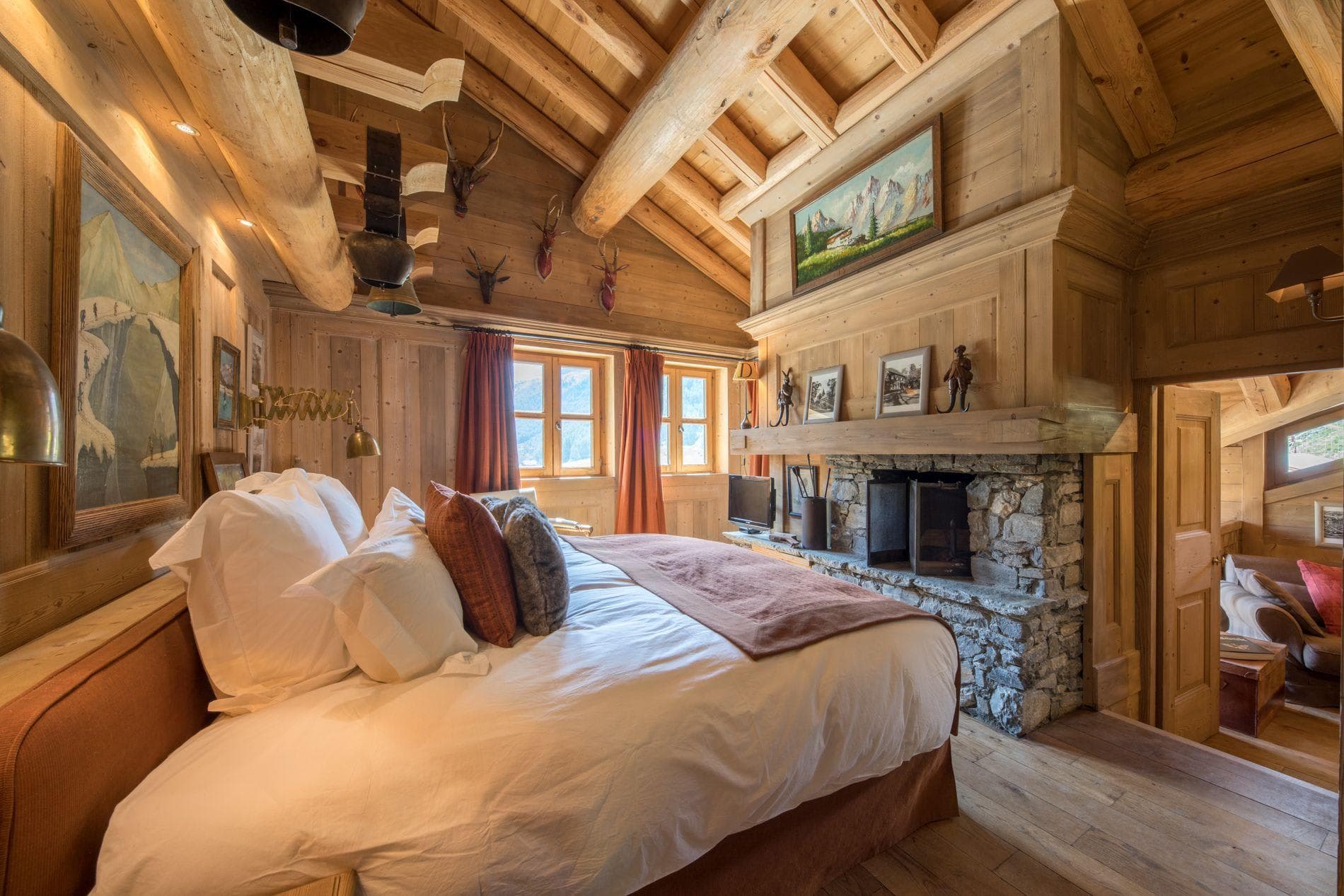 Primary bedroom with stone fireplace and vaulted log ceilings
