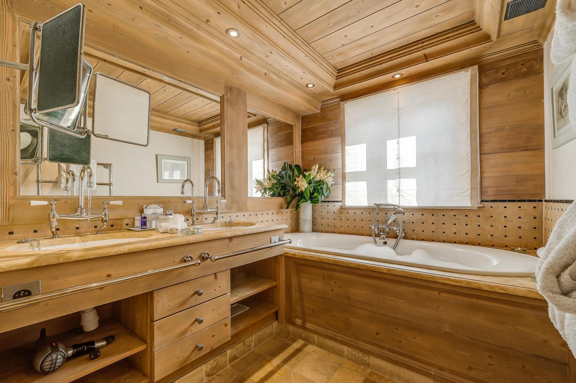 Bathroom featuring dual vanity with stone counters and deep soaking tub