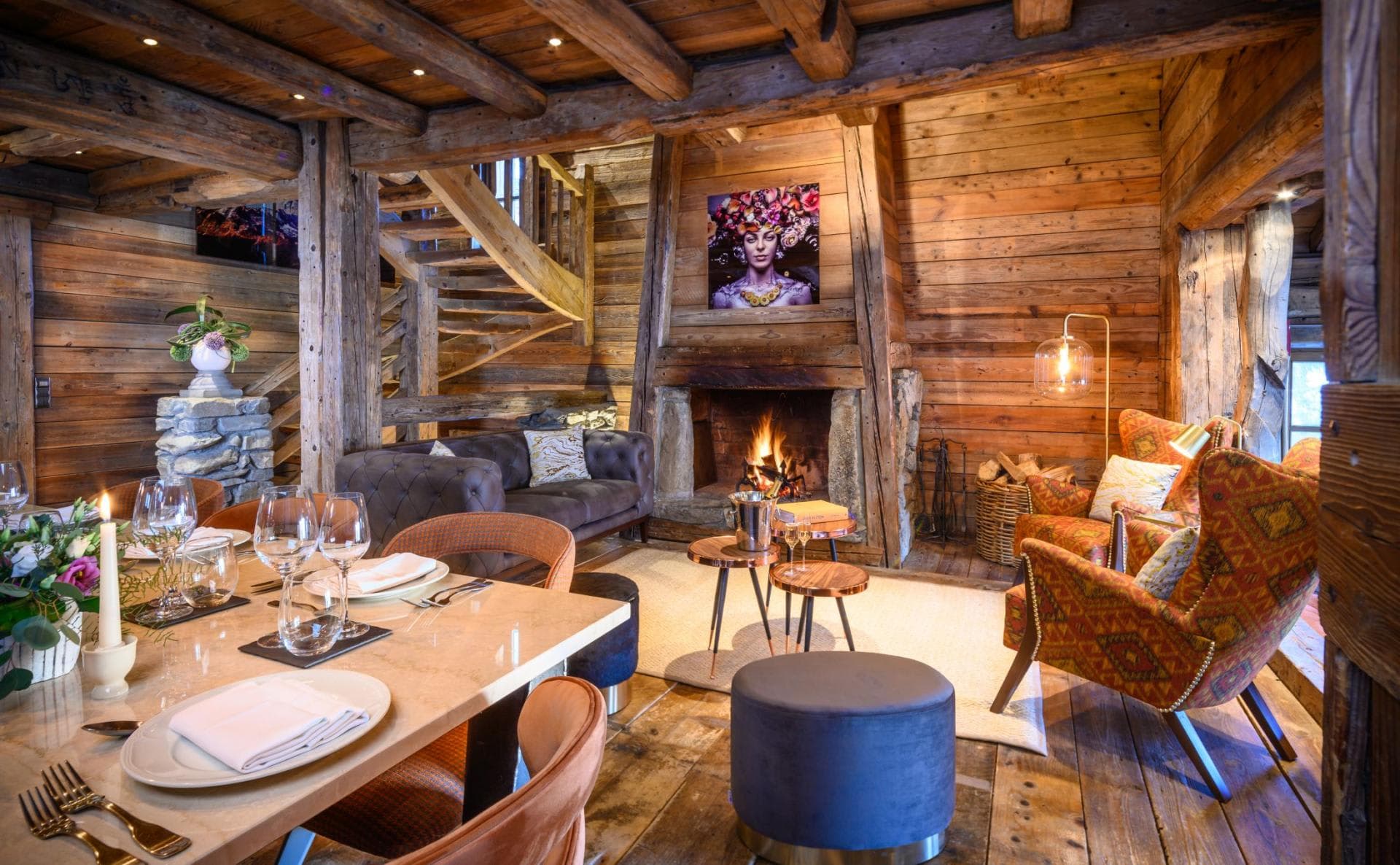 Open-concept living and dining area with wood-burning fireplace and exposed timber beams