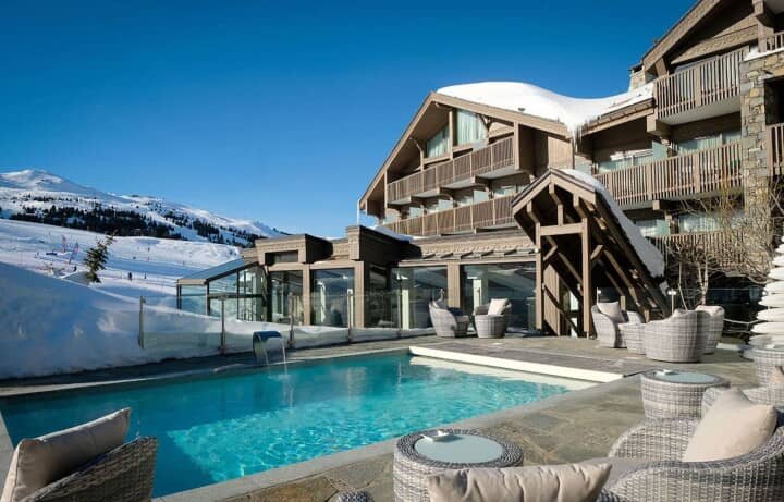 Heated outdoor pool with waterfall feature and ski slope views