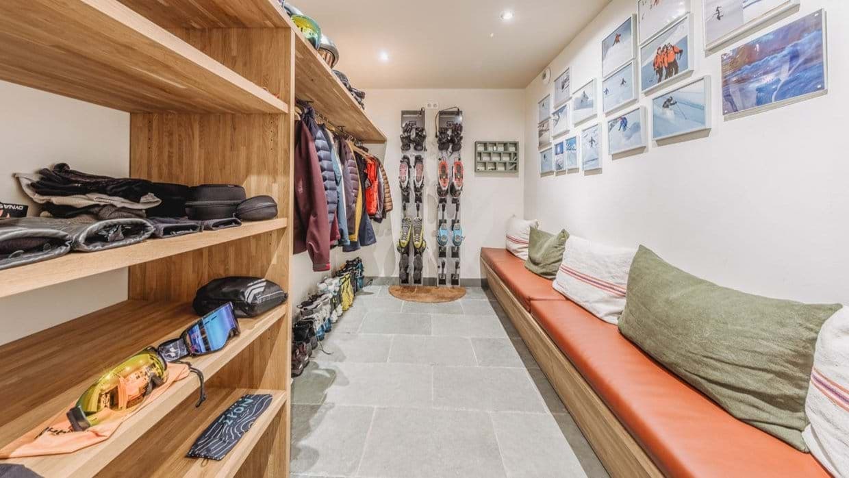 Ski room with wall-mounted racks, boot storage, and bench seating