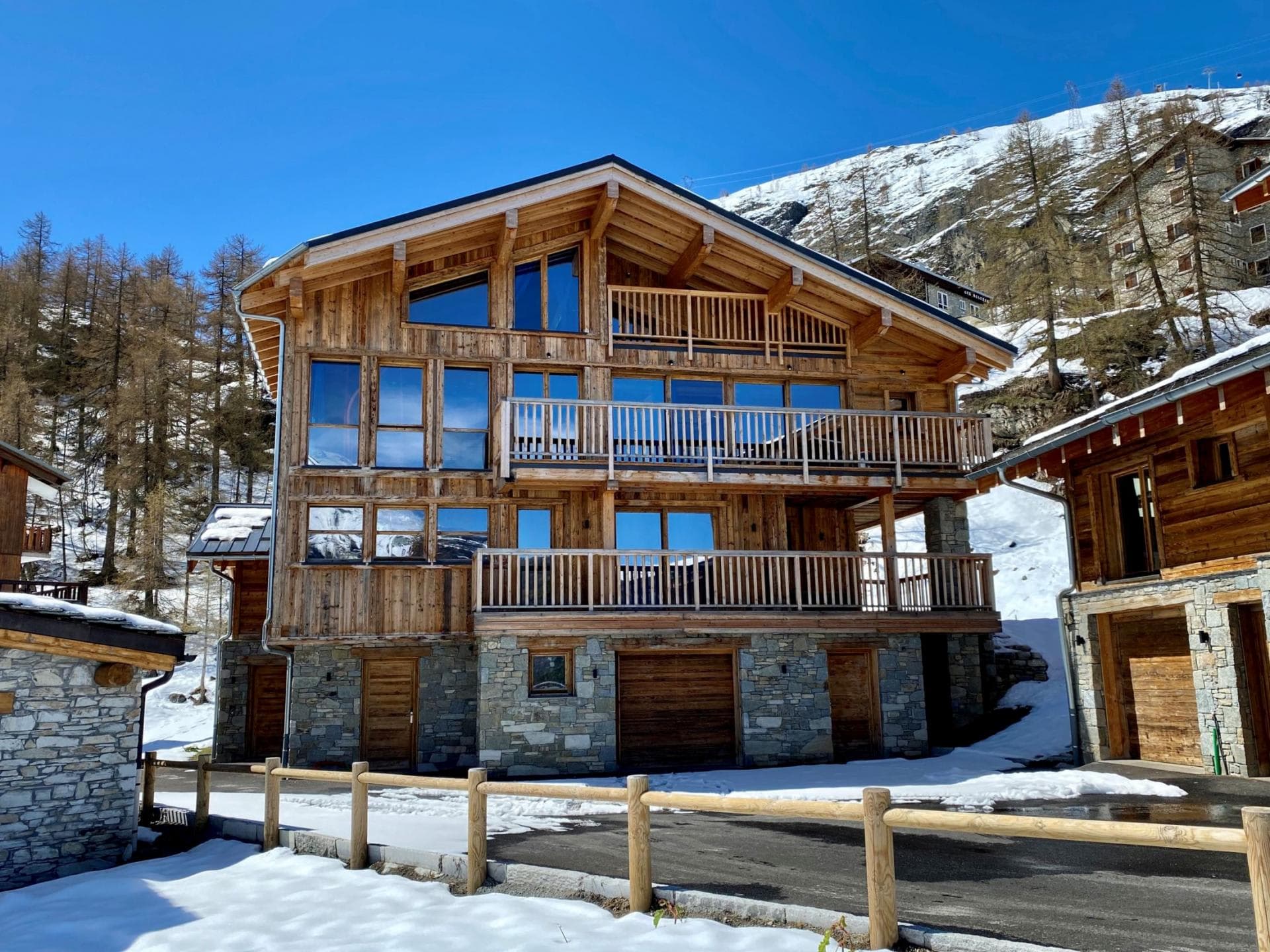 Ski-in chalet exterior featuring three levels of balconies and heated garage parking