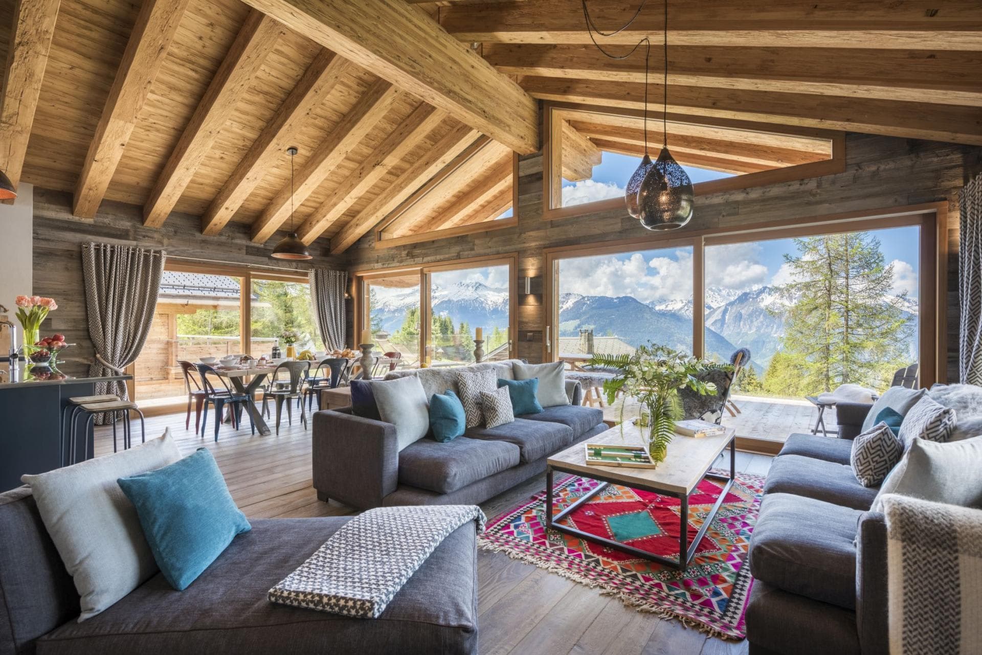 Open-plan living area with vaulted beam ceiling and panoramic mountain views