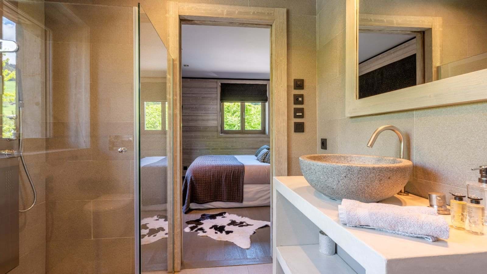 En suite bathroom with stone vessel sink and glass-enclosed shower