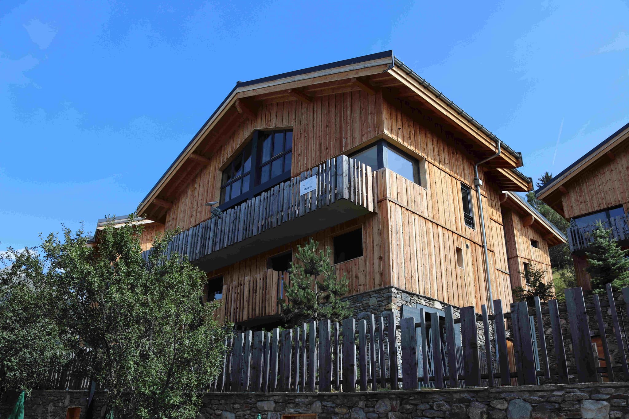 Timber-clad chalet exterior with private balcony and stone foundation