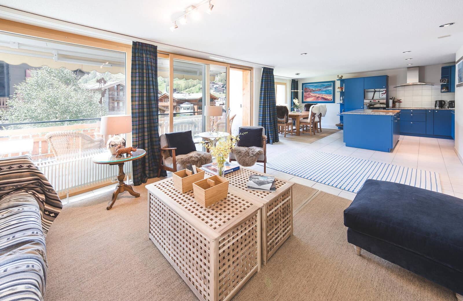 Open-plan living area with blue kitchen and balcony access