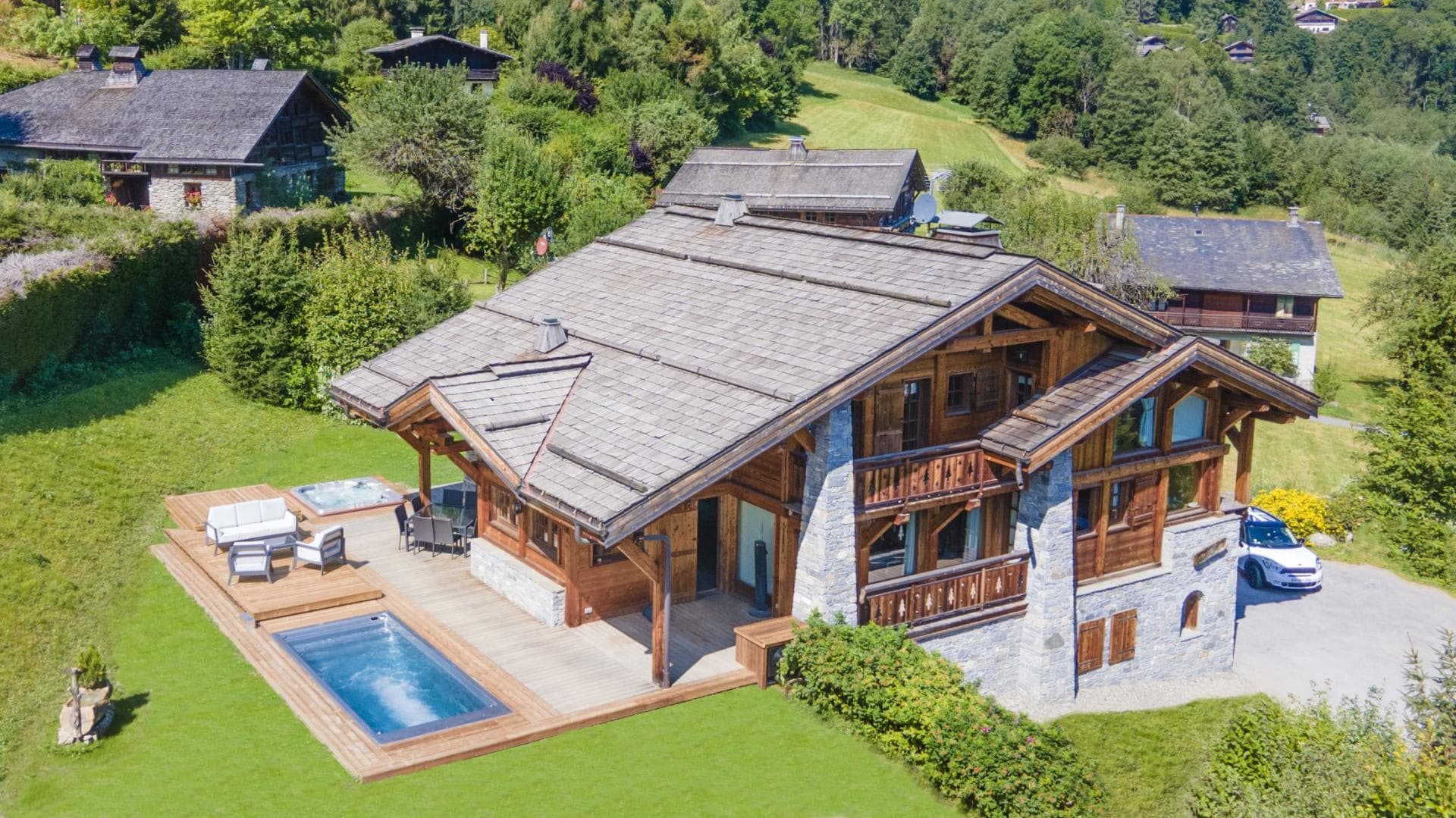 Chalet exterior with sun deck, outdoor pool, and hot tub