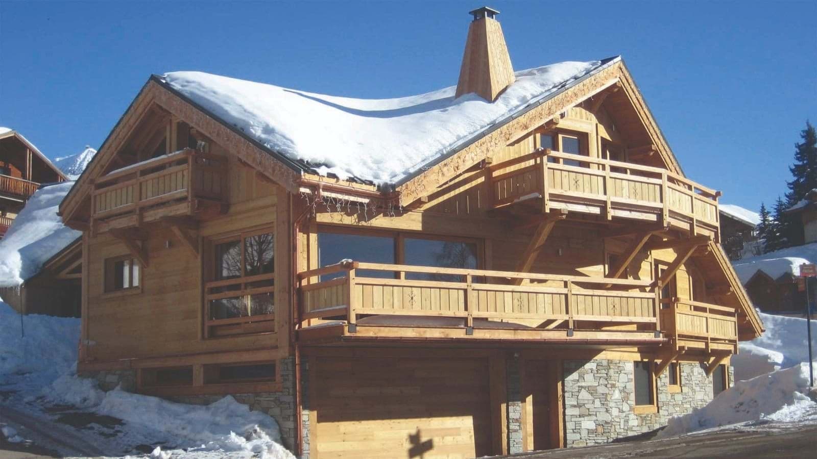 Chalet exterior featuring three tiered balconies and wood-paneled garage
