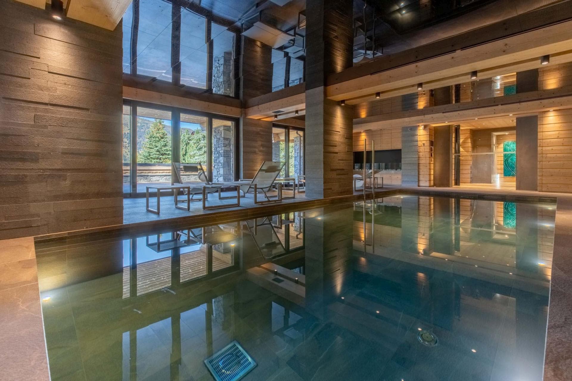 Indoor pool with lounge seating and floor-to-ceiling mountain views