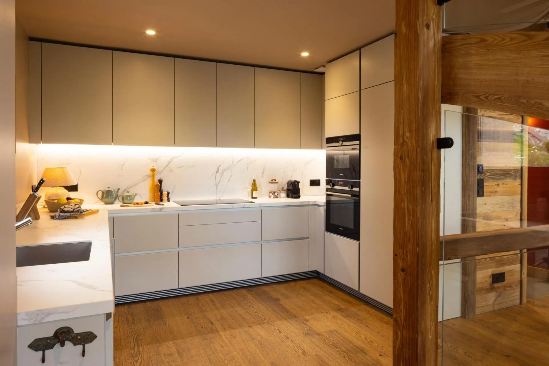 Open fitted kitchen with white cabinets and timber beams